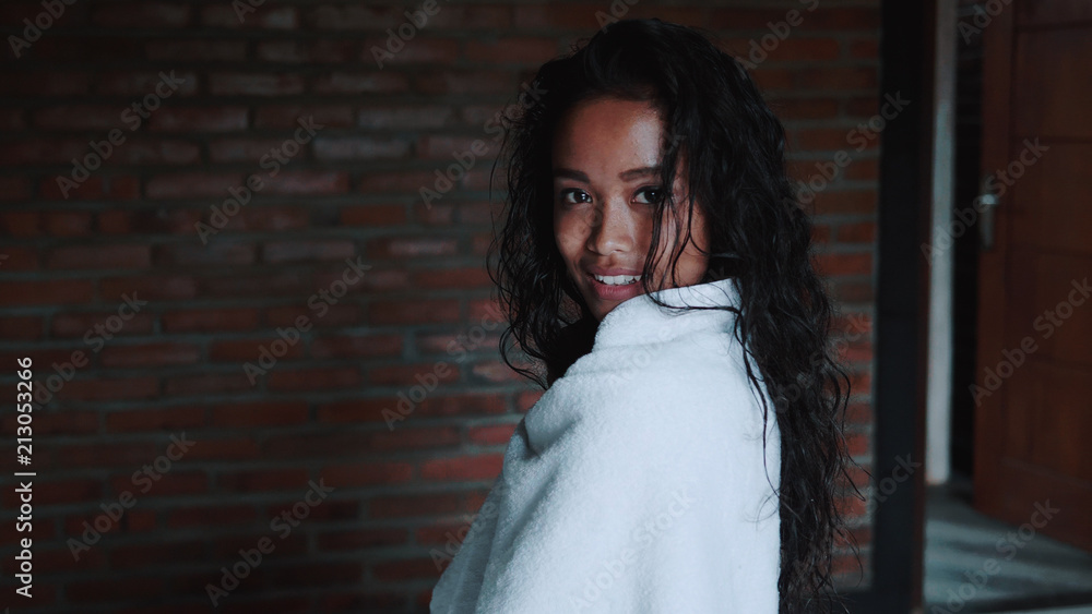 Fototapeta premium Beautiful lady after shower covered in white towel relaxing in her apartment. Portrait of fashion model girl indoors