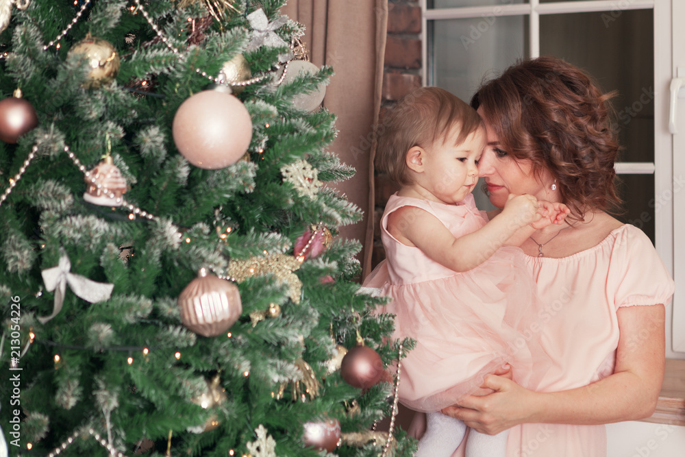 portrait of happy beautiful girl and mother sitting near Christmas tree portrait of happy beautiful girl and mother sitting near Christmas tree