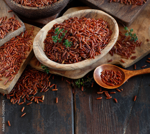Uncooked Red rice in a bowl with a wooden spoon