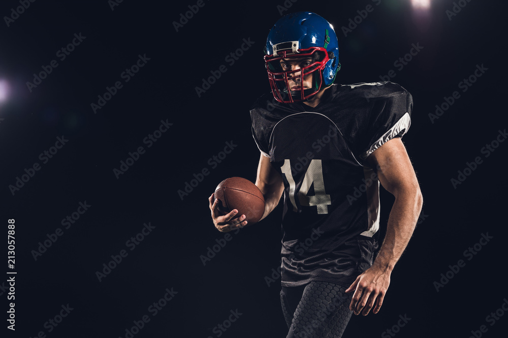 equipped american football player with ball isolated on black