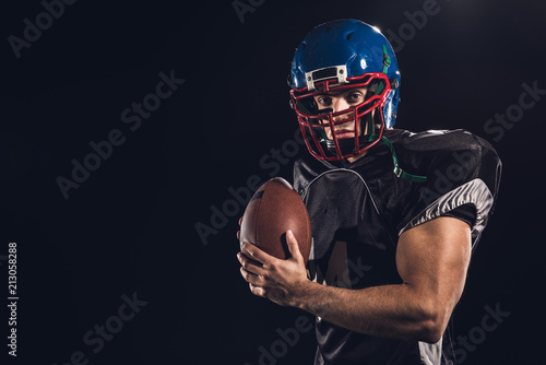 american football player with ball looking at camera isolated on black
