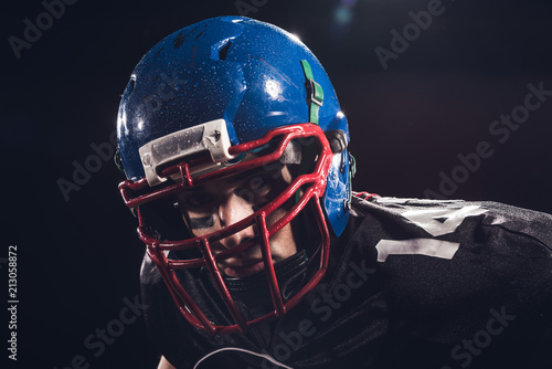 close-up portrait of serious american football player in helmet looking at camera isolated on black