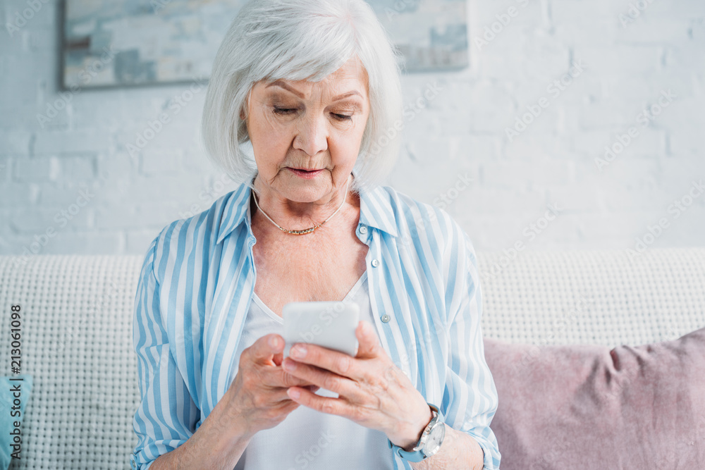 portrait of senior woman using smartphone while resting on couch at home portrait of senior woman using smartphone while resting on couch at home
