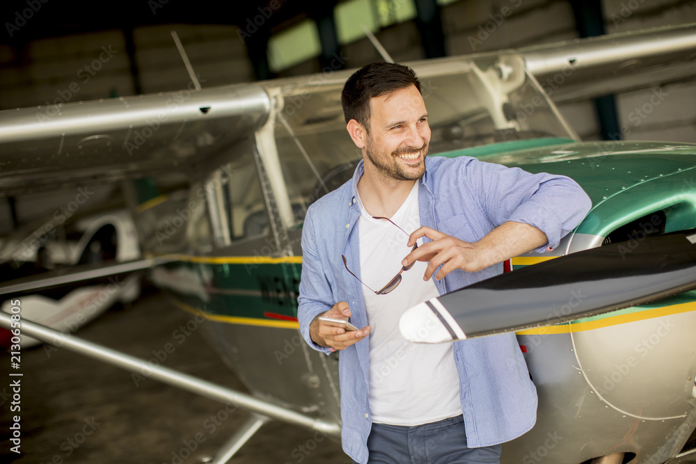 Young pilot checking airplane in the hangar Young pilot checking airplane in the hangar