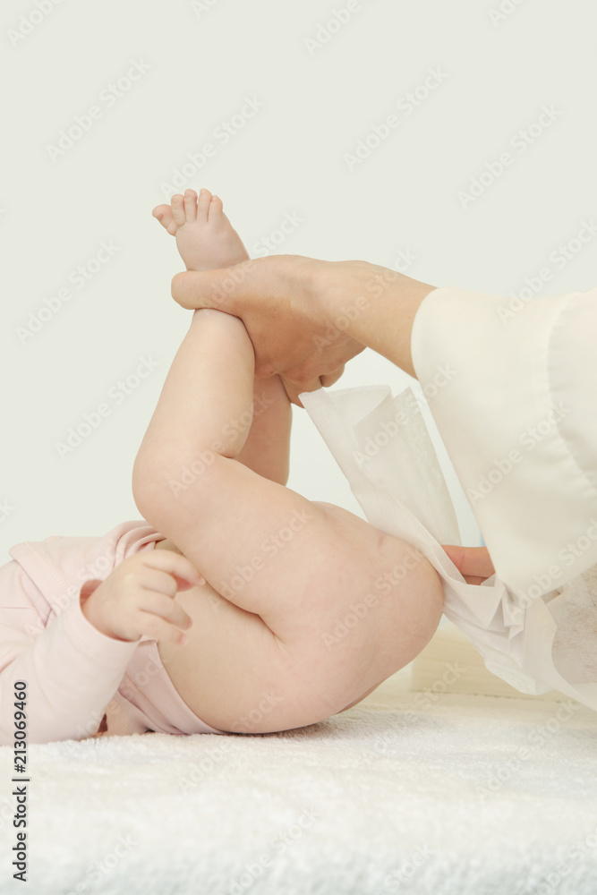 Newborn baby getting a diaper change: mom wiping baby's bottom with baby wipe