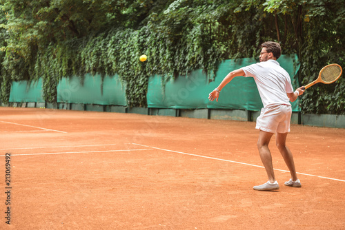 old-fashioned sportsman playing tennis with racket and ball on tennis court