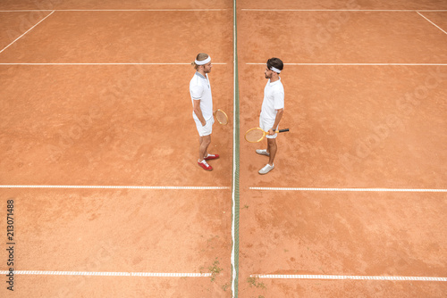 overhead view of tennis players in white sportswear with wooden rackets on court © LIGHTFIELD STUDIOS