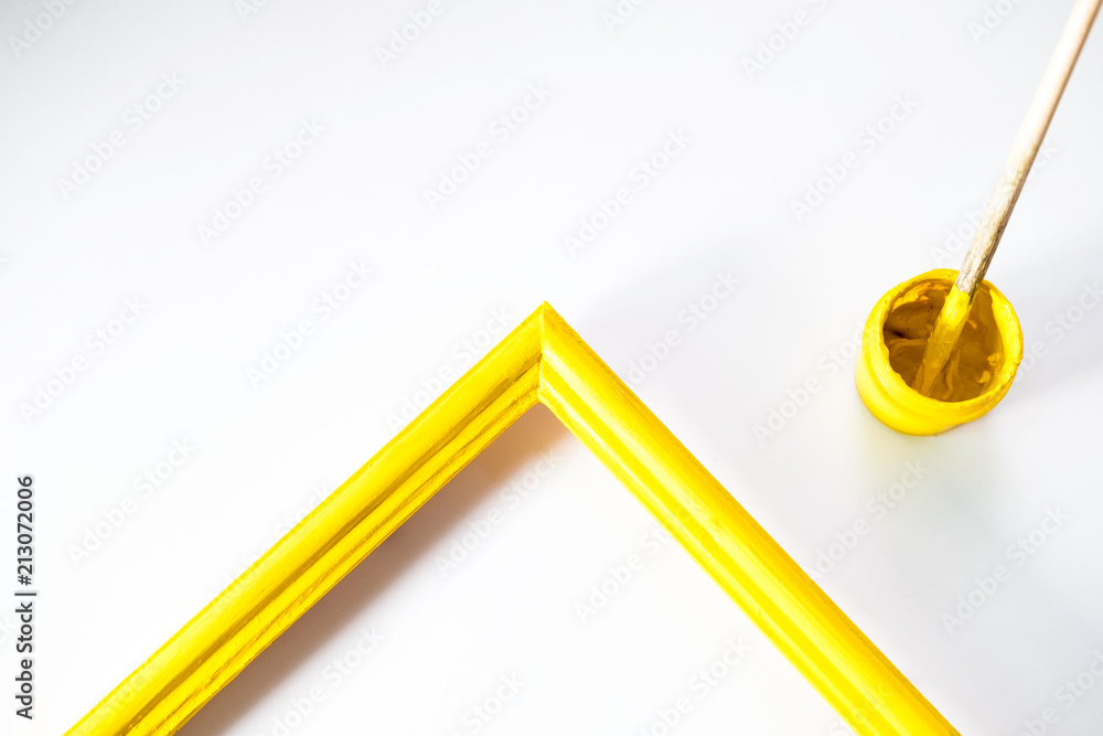 yellow wooden photo frame painted with gouache paint rough texture is next in a jar with a brush on a white background yellow wooden photo frame painted with gouache paint rough texture is next in a jar with a brush on a white background