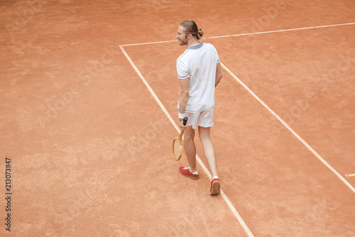 handsome tennis player with racket on brown court © LIGHTFIELD STUDIOS