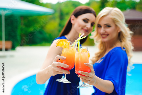 beautiful sexy women in bikini drinking a cocktails while relaxing in the swimming pool.