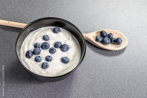 Wooden spoon behind a bowl full of homemade curd with blueberries