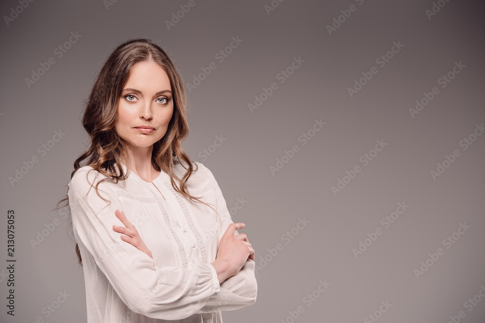 beautiful woman standing with crossed arms isolated on grey background beautiful woman standing with crossed arms isolated on grey background