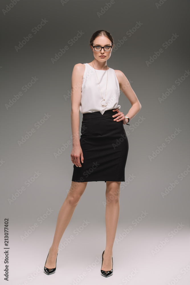 Fototapeta premium attractive businesswoman in eyeglasses posing on grey background