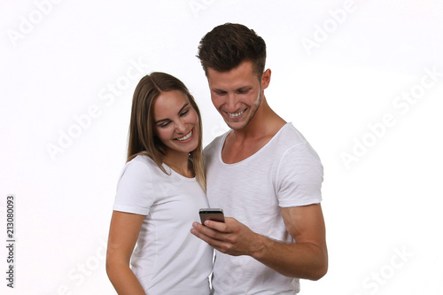 Hübsches junges Paar schaut lachend auf ein Smartphone in seiner Hand