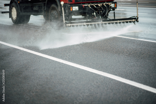 Cleaning sweeper machines washes the city asphalt road with water spray. photo