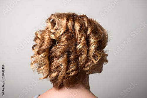 Hairstyle short curls on the head of a blonde rear view of turning the head to the right. A woman's hairdo.