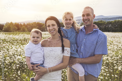 Happy family having fun on daisy field at sunset photo