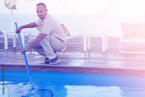 Pool cleaner during his work. Hotel staff worker cleaning the pool. Toning. © polack