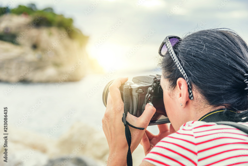 Woman with a camera photographing the sunset on the sea coast. Woman with a camera photographing the sunset on the sea coast.