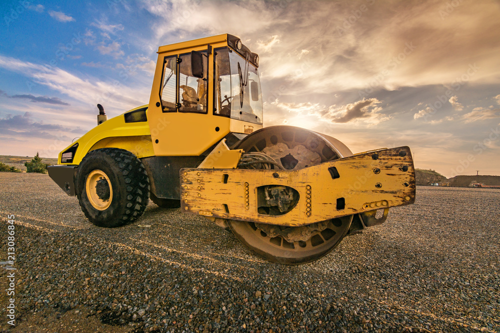 Yellow steamroller on asphalt road in sunlight Yellow steamroller on asphalt road in sunlight