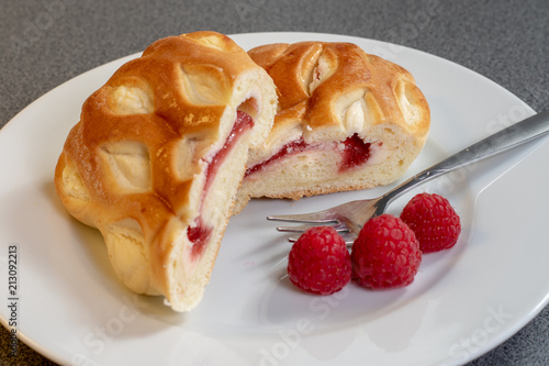 Ein Stück Himbeerkuchen dekoriert mit frischen Himbeeren auf einem weißen Kuchenteller photo