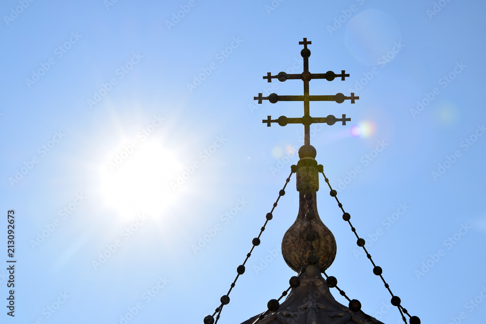 Romanian orthodox cross on sky and sun background in Cathedral of Curtea de Arges, Romanian Orthodox Monastery. Curtea de Arges, Romania.