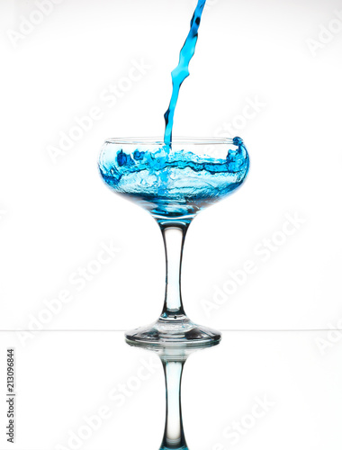 Splash from pouring blue water into the champagne glass