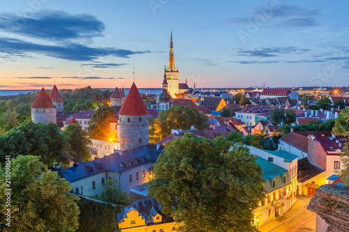 Magic white night view of old Tallinn with St. Olaf church. Illuminated medieval buildings, wall, towers and red roofs.