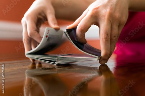 Tableau sur toile Person Shuffling a Deck of Cards on a Reflective Wooden Table