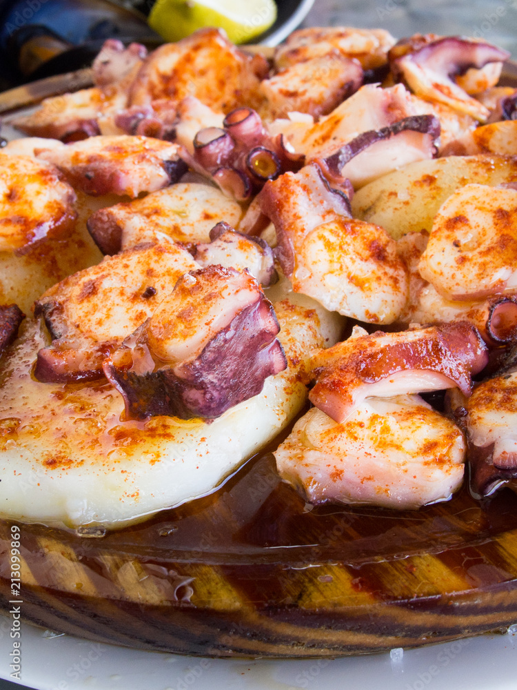 Octopus and potatoes cooked with paprika and olive oil on wood plate.  Galician food
