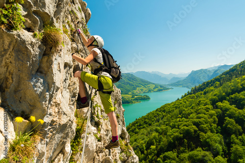 Beautiful young girl climbing Drachenwand via ferrata above scenic Mondsee lake, Austria