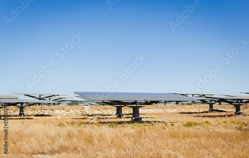 Rotatory solar panels on dry brown grass field on sunny day. Sustainable, renewable source, clean energy concepts photo