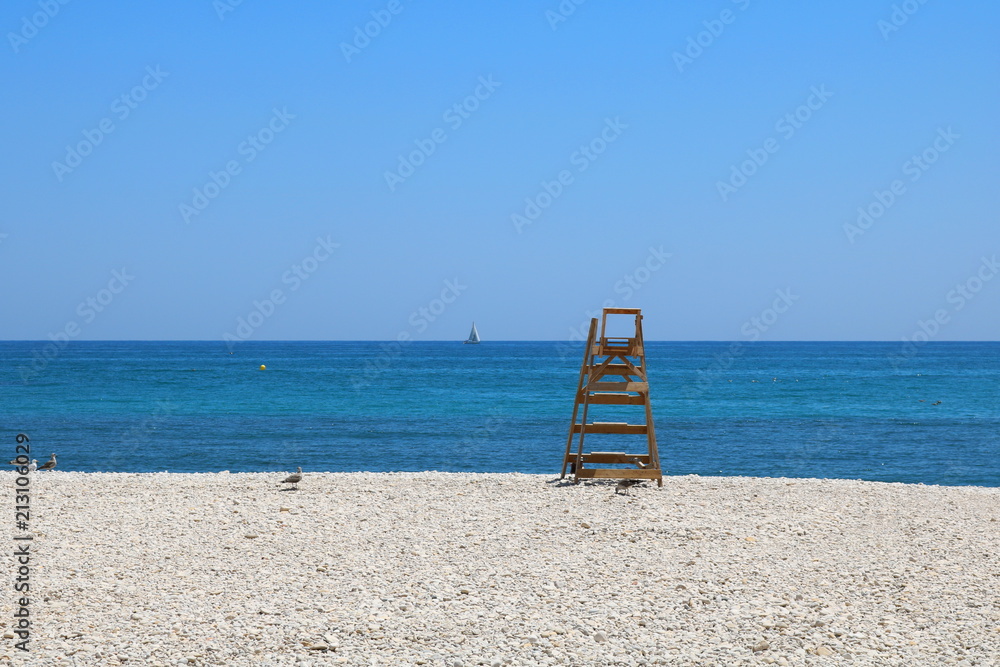 BEACH WITH THE BLUE SEA AND A SAILBOAT BEACH WITH THE BLUE SEA AND A SAILBOAT