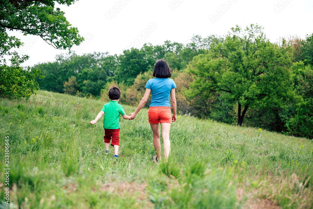 The boy walks with his mother in the meadow.