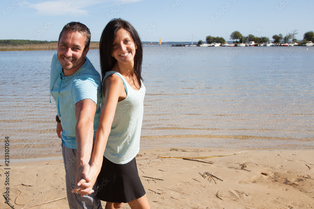 fun smiling couple holding hands on the beach fun smiling couple holding hands on the beach