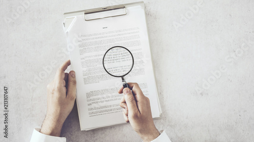 Man hands looking document with magnifying glass photo