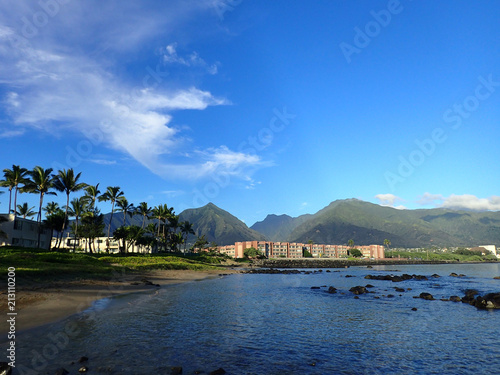 Kahului Bay with Hotel, coconut trees, and Iao Valley and surrounding mountains in the distance on West Maui on a beautiful day. photo