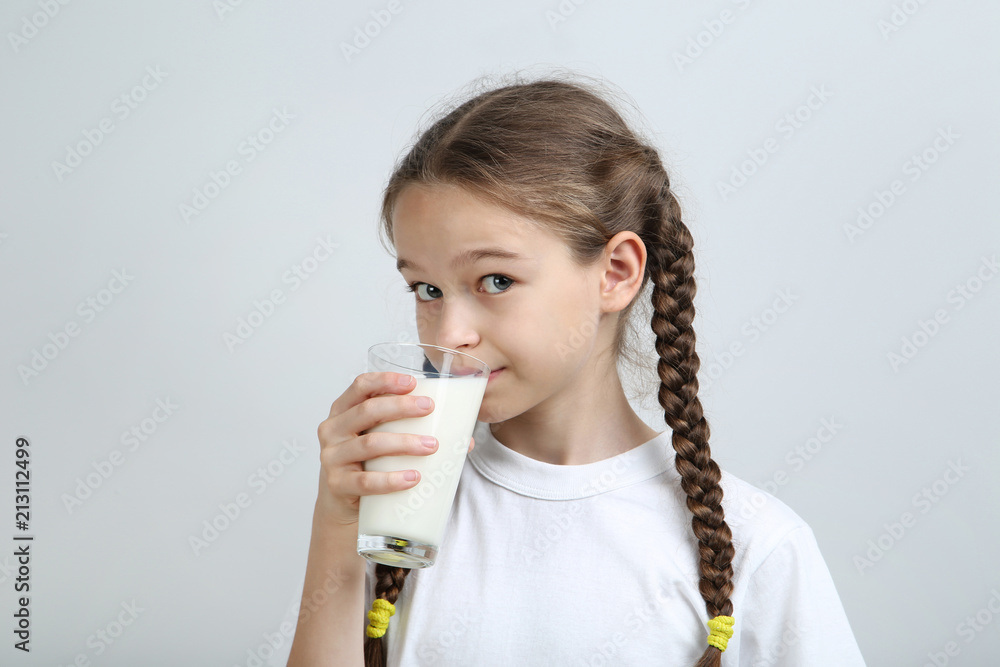 Young girl with glass of milk on grey background Young girl with glass of milk on grey background