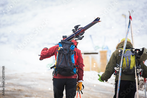 Back view of skiers carrying skis