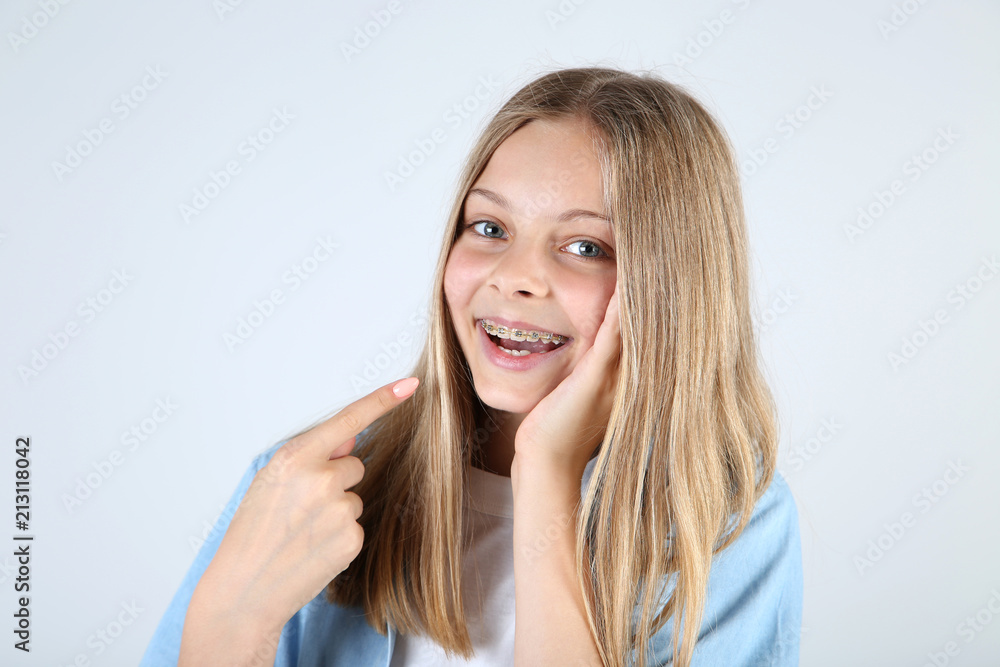 Young smiling girl with dental braces on grey background Young smiling girl with dental braces on grey background