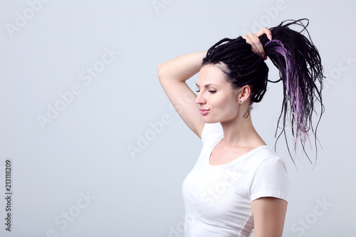 Cute young woman with dreadlocks on grey background