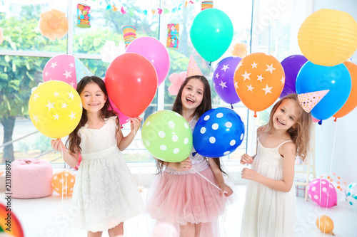 Cute girls with balloons at birthday party indoors
