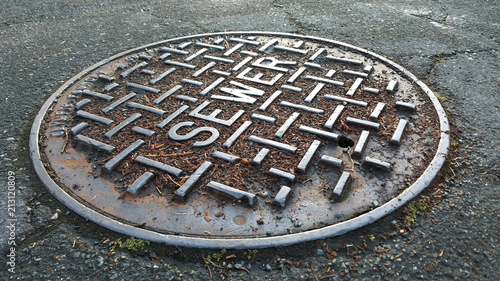 Sewer metal cap on the road after rain in close up