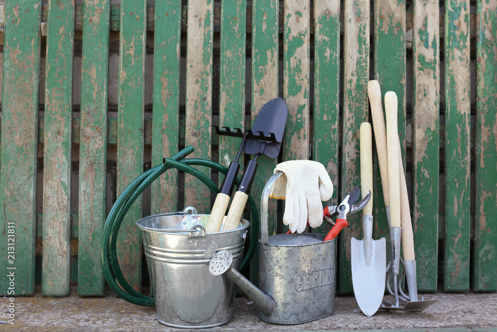 Set of gardening tools near wooden fence Set of gardening tools near wooden fence