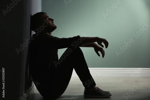 Depressed young man sitting on floor in darkness Fototapet