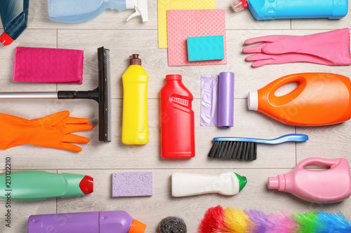 Flat lay composition with cleaning supplies on wooden background