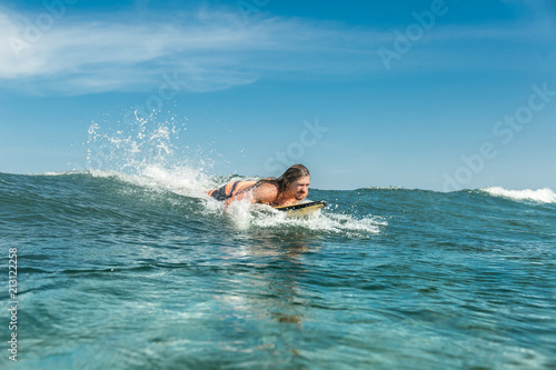male athlete swimming on surfing board in ocean at Nusa Dua Beach  Bali  Indonesia