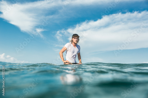 male surfer sitting on surfing board in ocean at Nusa Dua Beach  Bali  Indonesia