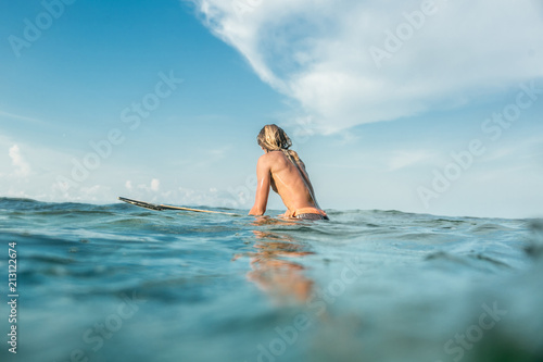 rear view of shirtless male surfer swimming on surfing board in ocean at Nusa Dua Beach  Bali  Indonesia