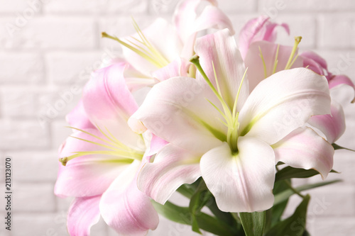 Beautiful blooming lily flowers on brick wall background